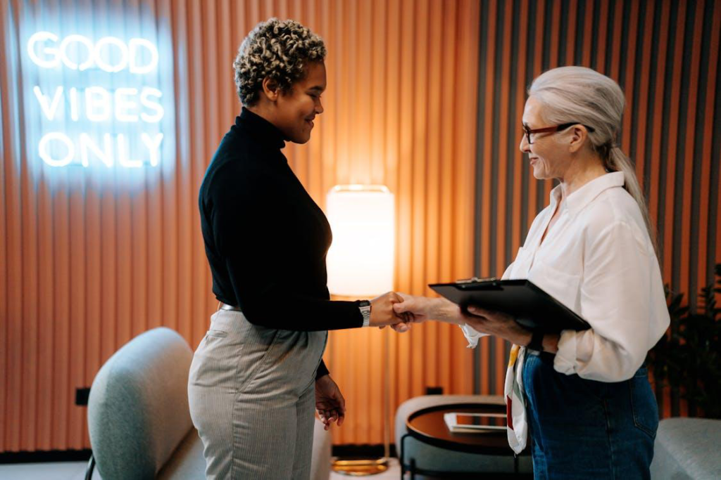 Two women shaking hands in an office meeting room