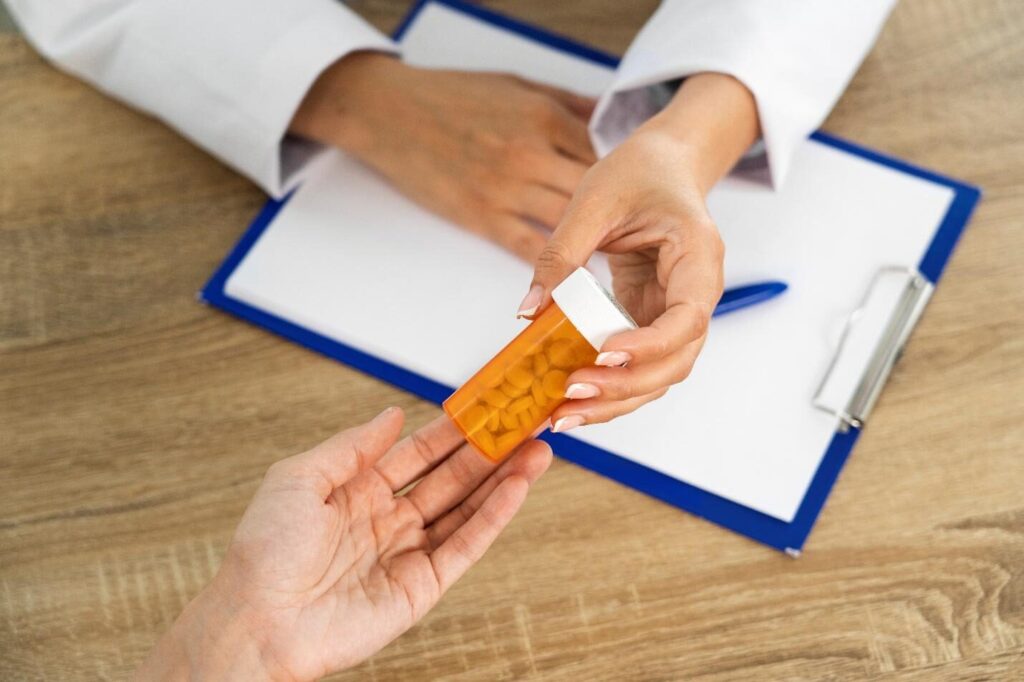 A picture of a doctor handing over pills to a patient